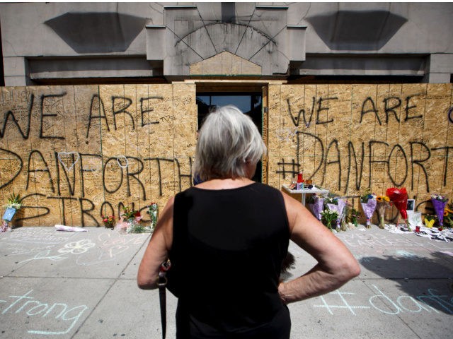 A woman stands at a makeshift memorial on Danforth Ave. where people were adding flowers a