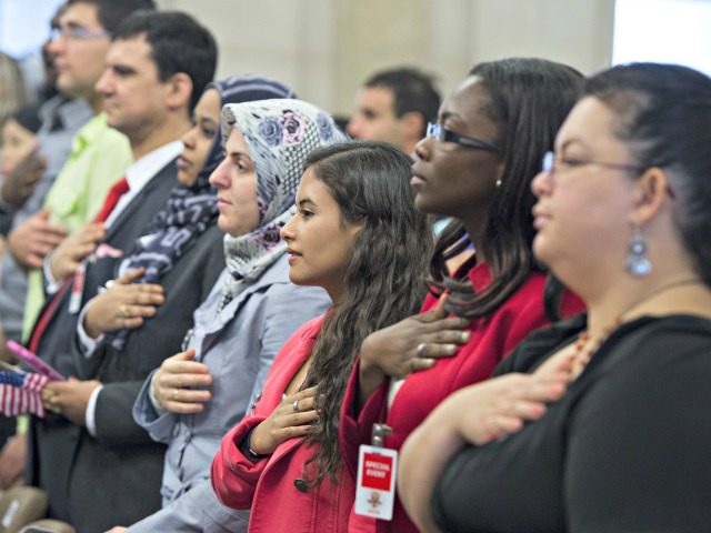 People recite the Pledge of Allegiance during a Naturalization Ceremony at the Justice Dep