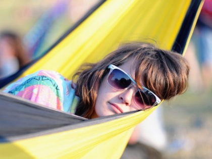 GLASTONBURY, ENGLAND - JUNE 24: A festival-goer relaxes in a hammock at sunset during Day 1 of the Glastonbury Festival on June 24, 2010 in Glastonbury, England. This year sees the 40th anniversary of the festival which was started by a dairy farmer, Michael Evis in 1970 and has grown …