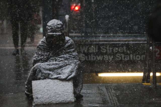 NEW YORK, NY - JANUARY 30: A homeless man sits in the falling snow in the Financial Distri