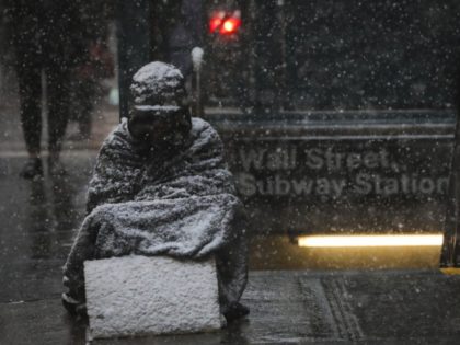 NEW YORK, NY - JANUARY 30: A homeless man sits in the falling snow in the Financial Distri