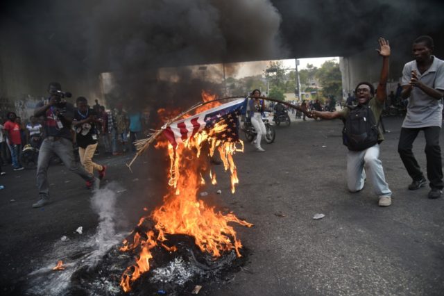 A protester burns a US flag during a demonstration in the Haitian Capital Port-au-Prince,