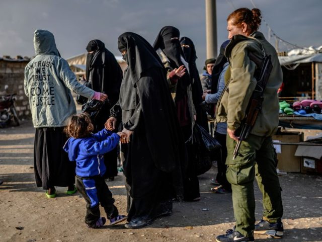 Veiled women, reportedly wives and members of the Islamic State, walk under the supervision of a female fighter from the Syrian Democratic Forces (SDF) at al-Hol camp in al-Hasakeh governorate in northeastern Syria on February 17, 2019. (Photo by BULENT KILIC / AFP) (Photo credit should read BULENT KILIC/AFP/Getty Images)