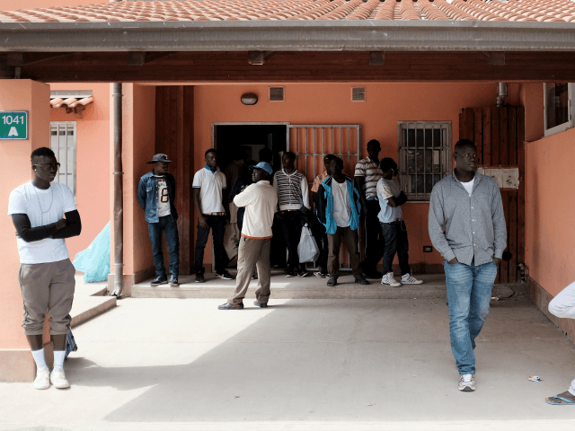 Migrants stand at the Cara Mineo, a hosting centre for asylum seekers, where about 3,200 migrants from North Africa, Ivory Coast, Pakistan, Syria, Afghanistan and other countries are staying in Mineo in the the province of Catania in Sicily on April 21, 2015, three days after a migrant boat capsized …