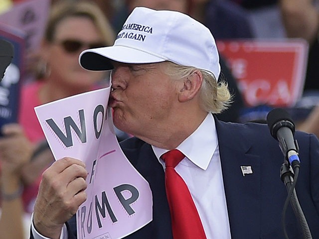 Republican presidential nominee Donald Trump kisses a "Women for Trump" placard during a r