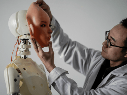 TOPSHOT - This photo taken on February 1, 2018 shows an engineer holding a silicon face against the head of a robot at a lab of a doll factory of EXDOLL, a firm based in the northeastern Chinese port city of Dalian. With China facing a massive gender gap and …