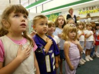 Sarah Henderson (L) and children from Mrs. Morrow's kindergarden class at Sunderland Elementry school recite the Pledge of Allegiance September 17, 2002 in Sunderland, Maryland.