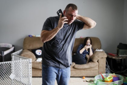 In this Nov. 28, 2018 photo, Tom Wolikow, a General Motors employee who is currently laid-off, left, takes a phone call at home alongside his fiance Rochelle Carlisle, right, in Warren, Ohio. It was working-class voters who bucked the area's history as a Democratic stronghold and backed Donald Trump in …