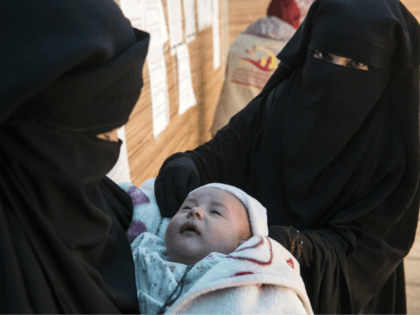 Displaced Syrian women hold a child as they wait at a makeshift clinic at the Internally Displaced Persons (IDP) camp of al-Hol in al-Hasakeh governorate in northeastern Syria on February 7, 2019. (Photo by FADEL SENNA / AFP) (Photo credit should read FADEL SENNA/AFP/Getty Images)