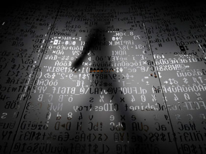 A picture taken on October 17, 2016 shows an employee walking behind a glass wall with machine coding symbols at the headquarters of Internet security giant Kaspersky in Moscow.