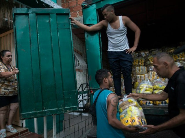 Neighbors download subsidized food distributed under a government program named "CLAP," in the Catia district of Caracas, Venezuela, Thursday, Jan. 31, 2019. An independent U.N. human rights monitor says economic sanctions are compounding a "grave crisis" in Venezuela.