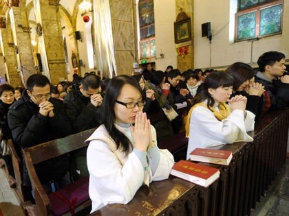 This picture taken on December 24, 2012 shows Chinese congregation members praying during the Christmas Eve mass at a Catholic church in Beijing. While China does not officially celebrate Christmas, its popularity continues to grow with non-Christians keen to see and feel the experience of Christmas. AFP PHOTO / WANG …