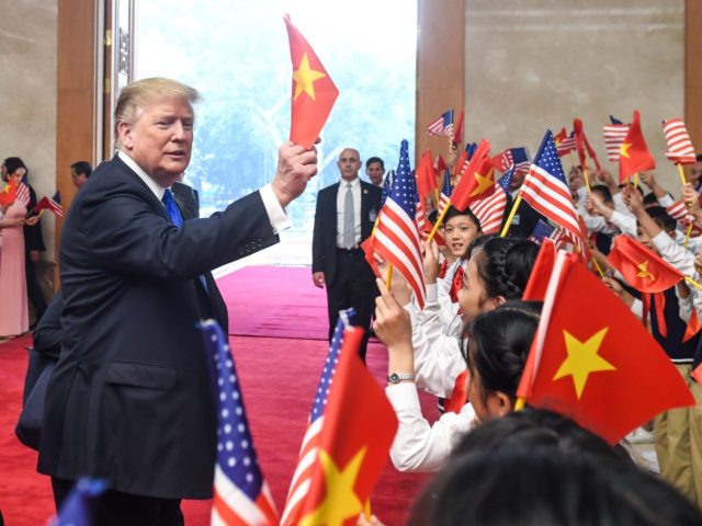 US President Donald Trump (C) waves a Vietnamese flag as Vietnam's Prime Minister Nguyen X