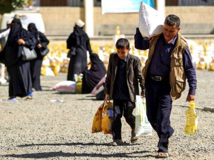 A Yemeni man and boy walk carrying bags of food aid provided by a local charity to families affected by the ongoing conflict, in the capital Sanaa on February 14, 2019. (Photo by MOHAMMED HUWAIS / AFP) (Photo credit should read MOHAMMED HUWAIS/AFP/Getty Images)