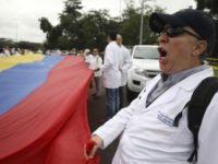 Colombia Venezuela Political Crisis Venezuelan doctors shout slogans against the government of Venezuela's President Nicolas Maduro at the International Bridge Tienditas, which has been blocked by the Venezuelan military, near Cucuta, Colombia, Sunday, Feb. 10, 2019, across the border from Tachira, Venezuela. The doctors, who crossed into Colombia for the protest, are demanding their nation’s military allow humanitarian aid into the country, while Venezuelan President Nicolas Maduro contends the aid delivery is part of a larger U.S. intervention to remove him from power. (AP Photo/Fernando Vergara) The Associated Press