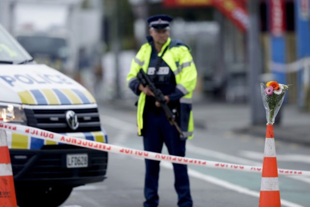 Flower rest at a road block, as a Police officer stands guard near the Linwood mosque, sit