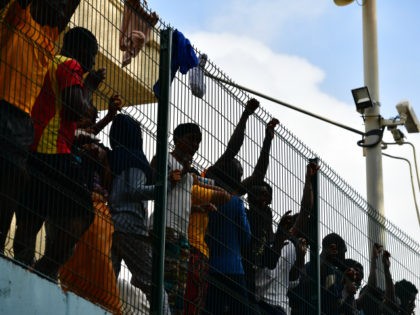 Migrants inside the Centre for Temporary Stay of Immigrants (CETI) cheers towards newly arrived African migrants which successfully breached the border from Morocco into the Spanish exclave of Ceuta on August 22, 2018 in Ceuta, Spain. This morning 100-150 mostly sub-saharan refugees crossed the barb wire fence from Morocco into …