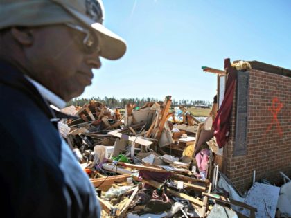 Bernard Reese stands next to the rubble of his aunt's home in which she survived a to