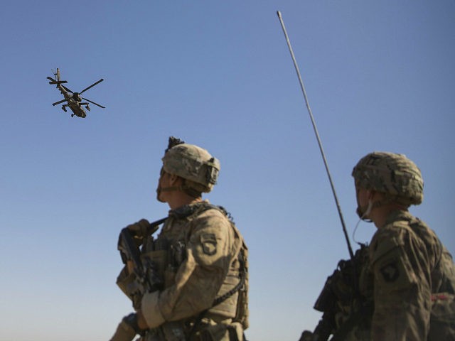This June 10, 2017 photo released by the U.S. Marine Corpsshows an AH-64 Apache attack helicopter provides security from above while CH-47 Chinooks drop off supplies to U.S. Soldiers with Task Force Iron at Bost Airfield, Afghanistan. Sixteen years into its longest war, the United States is sending another 4,000 …