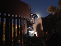 Migrants scale outdated border barrier in San Diego Sector. (File Photo: John Moore/Getty Images)