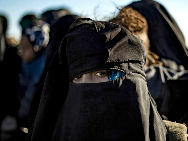 A woman looks on as she waits to be searched by members of the Kurdish-led Syrian Democrat