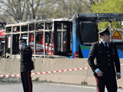 Itaian policemen work by the wreckage of a school bus that was transporting some 50 children on March 20, 2019 after it was torched by the bus' driver, in San Donato Milanese, southeast of Milan. - Italian police rescued some 50 children on March 20, 2019 after their driver threatened …