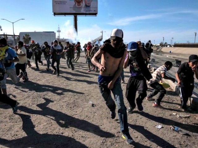 Migrants, mostly Hondurans, run along the Tijuana river near the El Chaparral border crossing in Mexico Photograph: Guillermo Arias/AFP/Getty