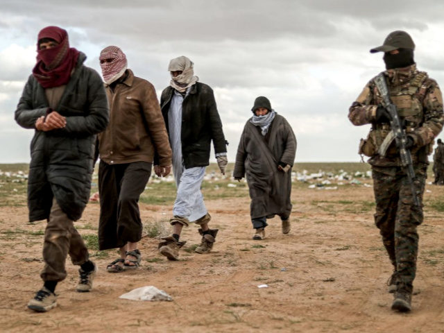 Men suspected of being an Islamic State (IS) group's fighter walk next to a member of the Kurdish-led Syrian Democratic Forces (SDF) as they wait to be searched after leaving the IS group's last holdout of Baghouz, in Syria's northern Deir Ezzor province on February 27, 2019.