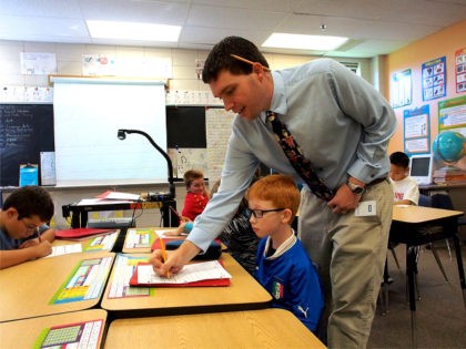 Christian Buzzerd, a teacher at Triadelphia Ridge Elementary School in Ellicott City, Maryland, helps a pupil write in cursive on Octber 15, 2013.