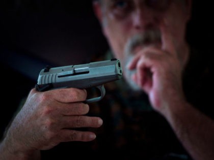 A member of the Georgia Security Force III% militia looks at another member's hand gun during a field training exercise July 28, 2017 in Jackson, Georgia.