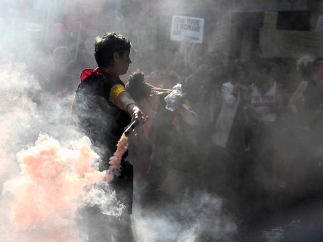 A protester holds a smoke bomb during a march of members of feminist groups and associatio