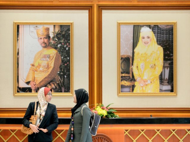 Two woman walk past portraits of Brunei Sultan Hassanal Bolkiah (L) and Queen Saleha (R) at the prime minister's complex in Bandar Seri Begawan on April 24, 2013 ahead of the start of the Association of Southeast Asian Nations (ASEAN) summit. Southeast Asian leaders are meeting in Brunei hoping to …