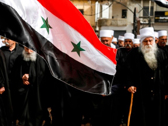 A Syrian national flag is seen before elderly Druze men attending a protest against US President Donald Trump's recognition of Israel's annexation of the Golan Heights, in the Druze village of Buqata in the Israeli-annexed territory on March 30, 2019. (Photo by JALAA MAREY / AFP) (Photo credit should read …