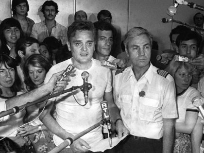 Michel Bacos (D), le commandant de bord de l'Airbus détourné par sept pirates de l'air, et l'un des 14 otages français parmi les 104 otages retenus pendant une semaine sur l'aéroport ougandais d'Entebbe, répondent à la presse à leur arrivée à Paris le 05 juillet 1976. Le reste des otages, …