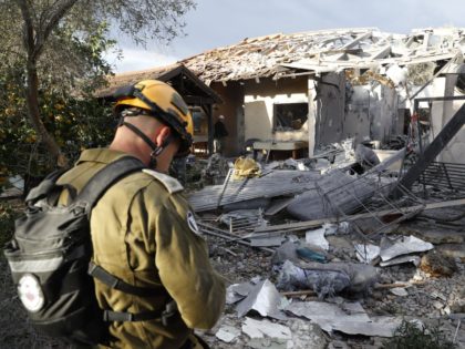 A general view shows an emergency responder inspecting a damaged house after it was hit by