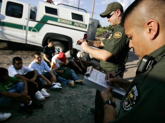NOGALES, AZ - AUGUST 30: U.S. Border Patrol agents, David Macias (R) and Kurt Dannawitz, process a group of illegal aliens August 30, 2005 in Nogales, Arizona. The governors of New Mexico and Arizona have declared a state of emergency along the border due to drug trafficking, illegal immigration and …