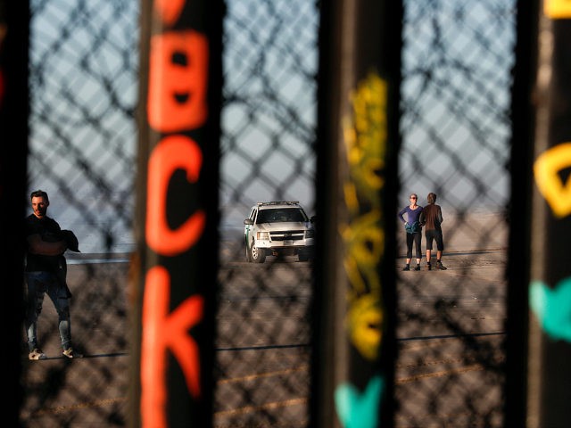 A U.S. border patrol car and tourists are seen in Imperial Beach, Calif., through the U.S.