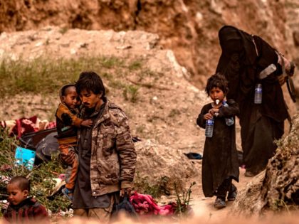 TOPSHOT - People said to be members of the Islamic State (IS) group by the US-backed Syrian Democratic Forces (SDF), exit with children from the village of Baghouz in the eastern Syrian province of Deir Ezzor, on March 14, 2019. (Photo by Delil souleiman / AFP) (Photo credit should read …