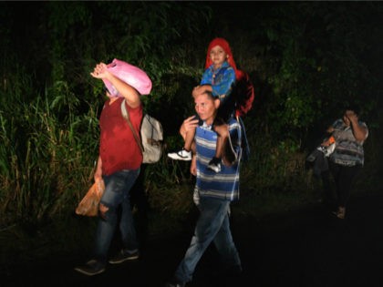 A man carries a child on his shoulders as Honduran migrants, part of the second caravan to