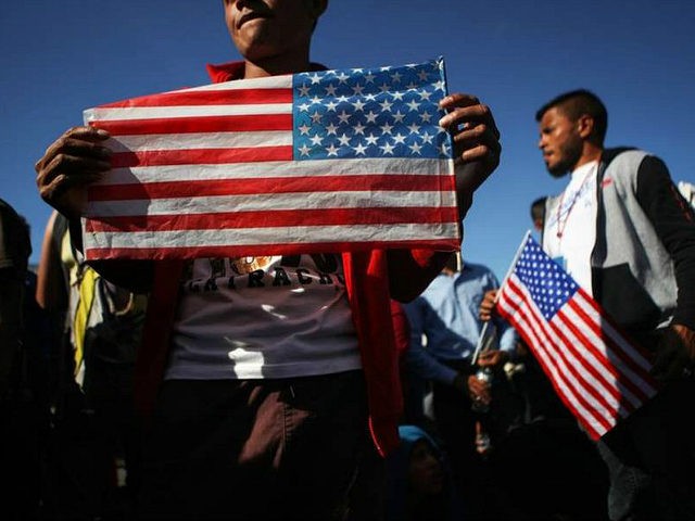 TIJUANA, MEXICO - NOVEMBER 25: Migrants hold American flags during a peaceful march shortl