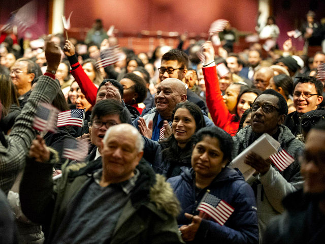Newly sworn in US citizens celebrate and wave US flags during a naturalization ceremony at