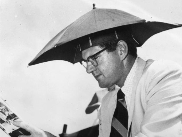 Warren Mitchell, a representative of Pan American Airways, wearing a small umbrella on his head while watching a Davis Cup match between Australia and the USA at White City tennis courts, Sydney. (Photo by Keystone/Getty Images)
