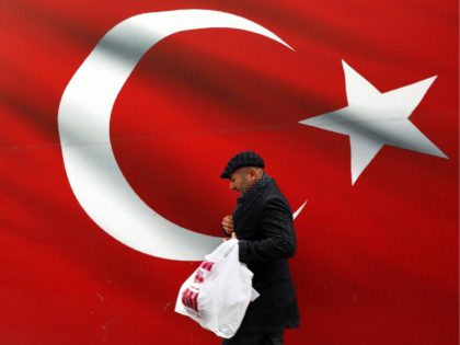 A man walks by a giant Turkish flag in Ankara, Turkey, Sunday, March 31, 2019. Turkish citizens have begun casting votes in municipal elections for mayors, local assembly representatives and neighborhood or village administrators that are seen as a barometer of Erdogan's popularity amid a sharp economic downturn. (AP Photo/Ali …
