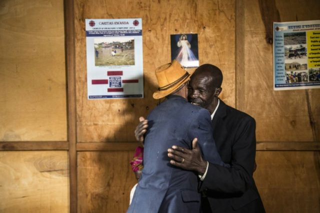 Jean-Bosco Gakwenzire, 65, of Tutsi ethnicity, embraces his old school mate Pascal Shyirahwamaboko (R), 68 with his wife Rose (hidden), both Hutu In Rwanda, the long, slow journey to forgiveness