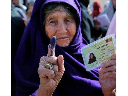 An elderly female Afghan voter shows her inked finger after she cast her ballot at a local