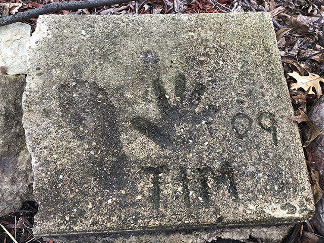 A slab of concrete sits in the backyard of the house where Timmothy Pitzen used to live in Aurora, Ill., Thursday, April, 4, 2019. The man who lives in the house now, Pedro Melendez, says he didn't know the boy but saved the concrete slab with Tim's name, handprint and …