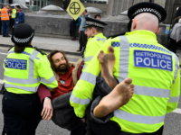 British police officers carry an activist as they remove them from Waterloo Bridge on the second day of an environmental protest by the Extinction Rebellion group, in London on April 16, 2019. - Environmental protesters from the Extinction Rebellion campaign group started a programme of demonstrations designed to block five …