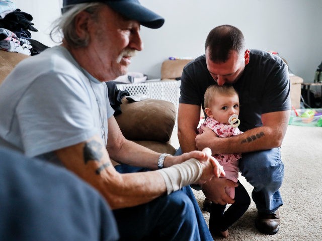 Tom Wolikow, right, holds his daughter Annabella alongside his father John, left, at their home Wednesday, Nov. 28, 2018, in Warren, Ohio. Even though unemployment is low, the economy is growing and U.S. auto sales are near historic highs, GM is cutting thousands of jobs in a major restructuring aimed …