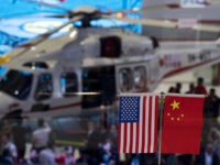 This picture taken on November 6, 2018 shows a Chinese and US flag at a booth during the first China International Import Expo (CIIE) in Shanghai. - There is a notable absentee among the dozens of national pavilions at a massive Chinese import fair -- the United States -- a …