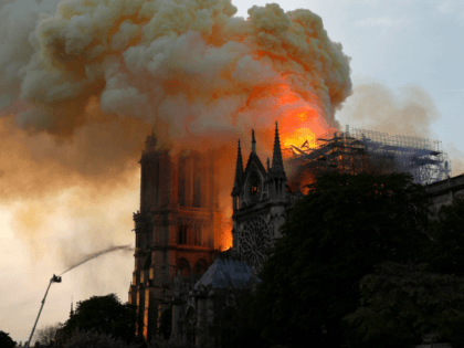 A firefighter uses a hose to douse flames and smoke billowing from the roof at Notre-Dame